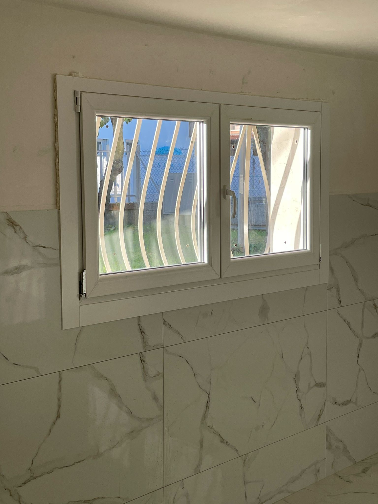Finestra a due ante in un bagno con rivestimento in marmo
